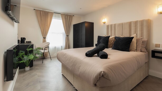A hotel room with a large bed, a desk with a computer, a chair, and a potted plant. - Bold St | Football & Nightlife | Centre City Stay (Liverpool)