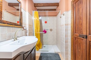Une salle de bain avec un lavabo, une douche et une porte en bois.