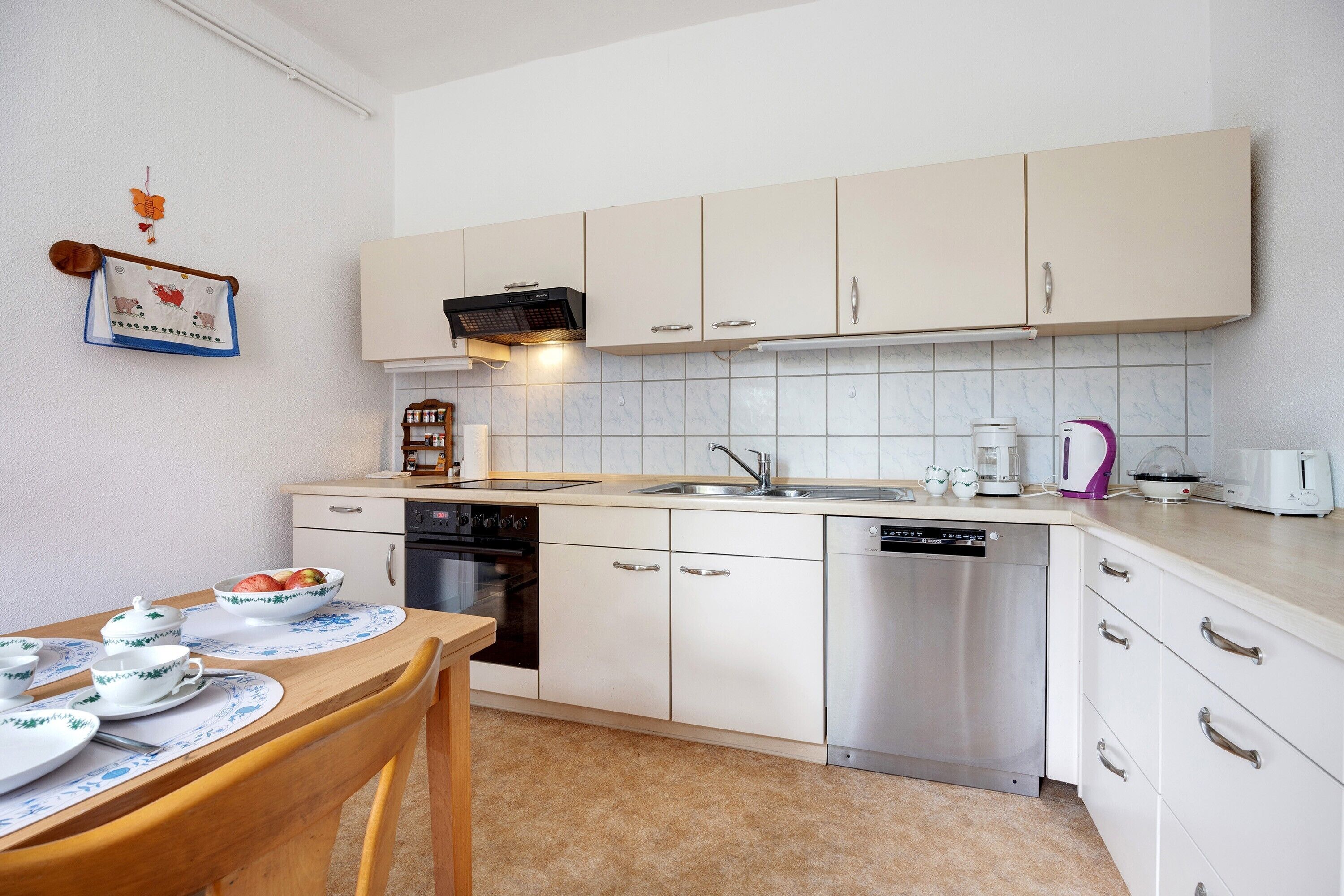 A kitchen with white cabinets, a dishwasher, a stove, and a sink.