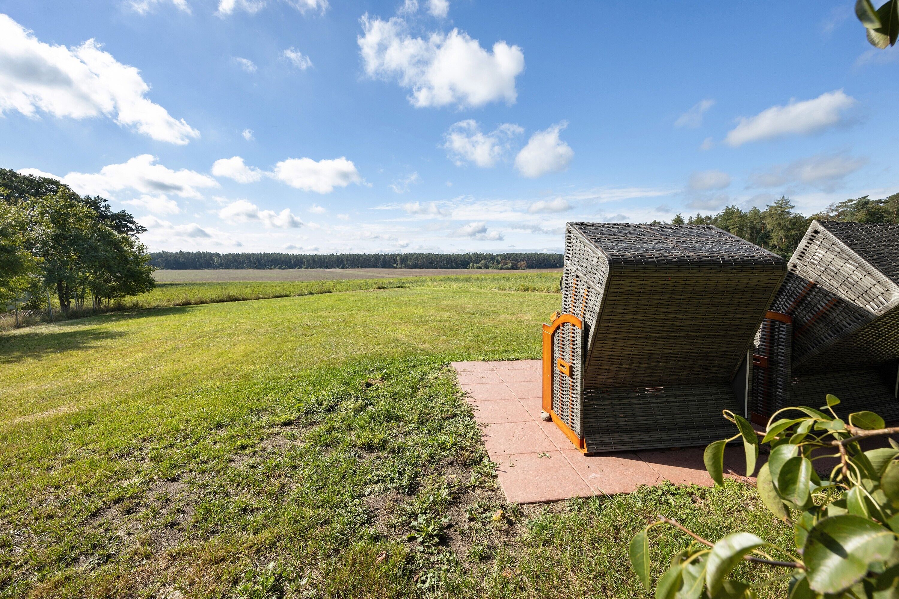Een gebouw met een schuin dak, een verhard pad en een grasveld op de achtergrond.