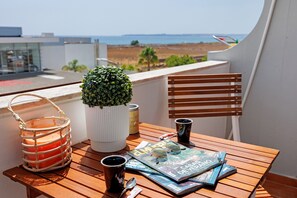Ett träbord med ett tidningsställ, en växt, ett ljus och en kopp.