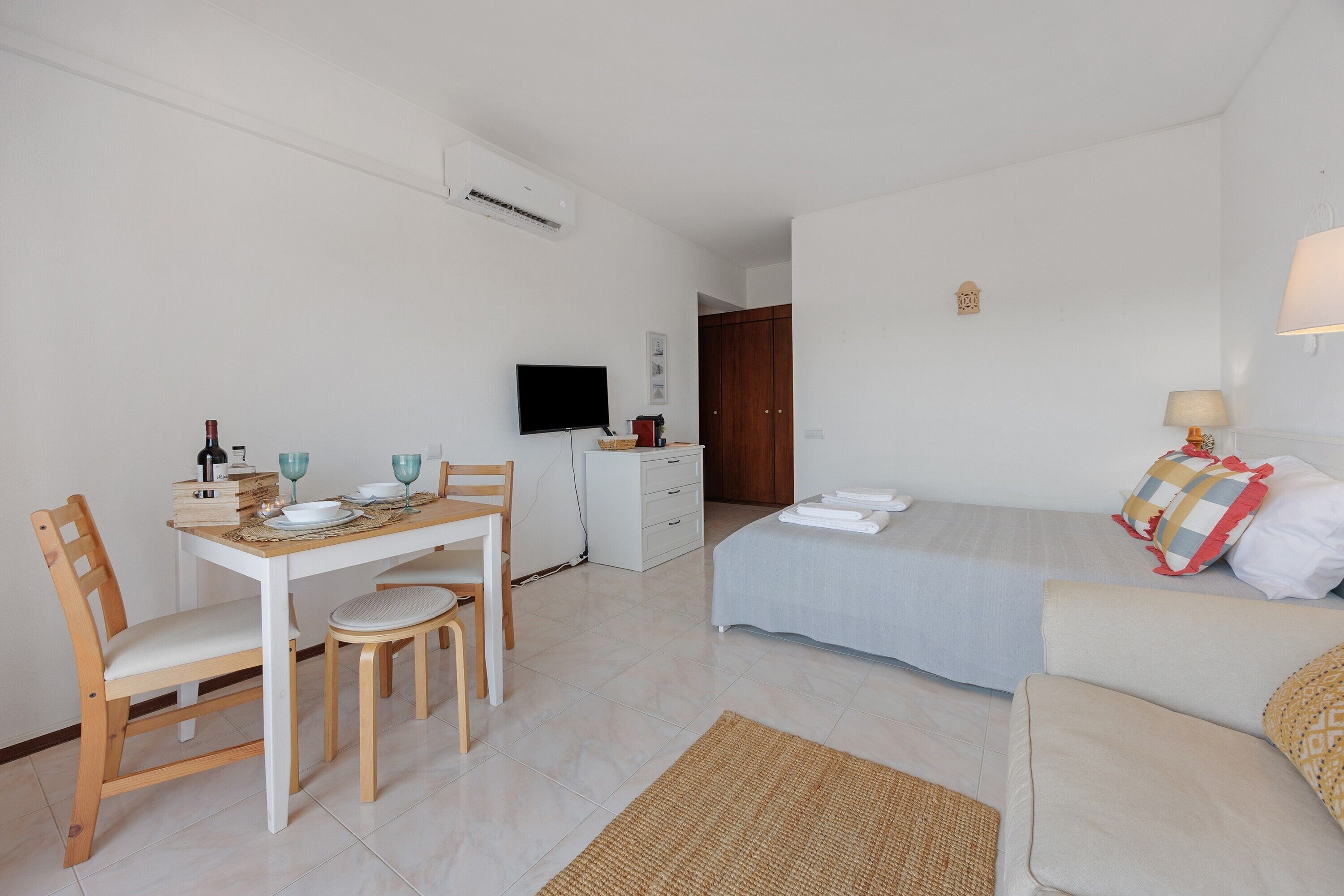 Une pièce comprenant un lit, un canapé, une table à manger avec des chaises, un téléviseur et une armoire.