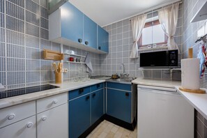 Ett kök med blå skåp, en mikrovågsugn och en diskmaskin.