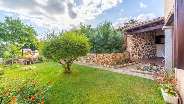 A well-maintained garden with a stone wall, a small tree, and a patio area. - Three-room apartment "The Flamingos" (Suaredda-traversa)