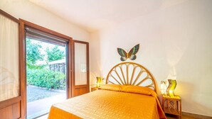 A bedroom with a bed, a butterfly wall decoration, a bedside lamp, and a view of greenery outside. - Three-room apartment "The Flamingos" (Suaredda-traversa)