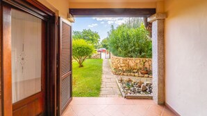 A narrow corridor leading to a garden with a stone wall and a variety of plants. - Three-room apartment "The Flamingos" (Suaredda-traversa)