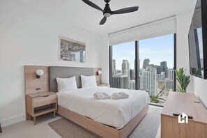 Een moderne hotelkamer met een groot bed, een nachtkastje, een bureau en uitzicht op de stad.