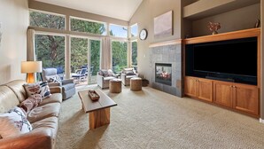 A spacious living room with a leather couch, ottomans, a coffee table, and a fireplace. - Brighter Days 3 Bedroom Townhouse (Redmond)