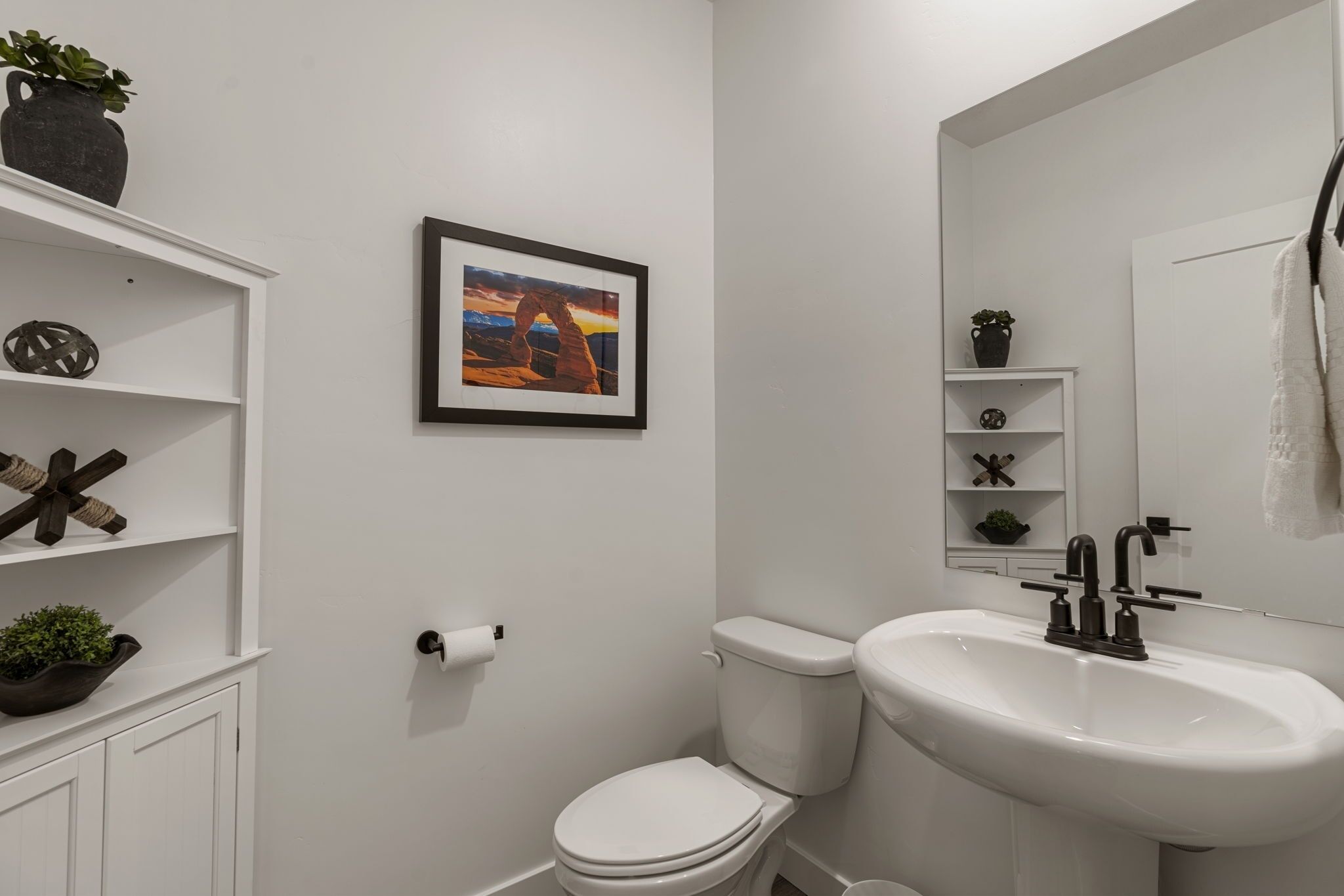 Une salle de bain moderne équipée de toilettes, d’un lavabo et d’étagères ornées d’objets décoratifs.