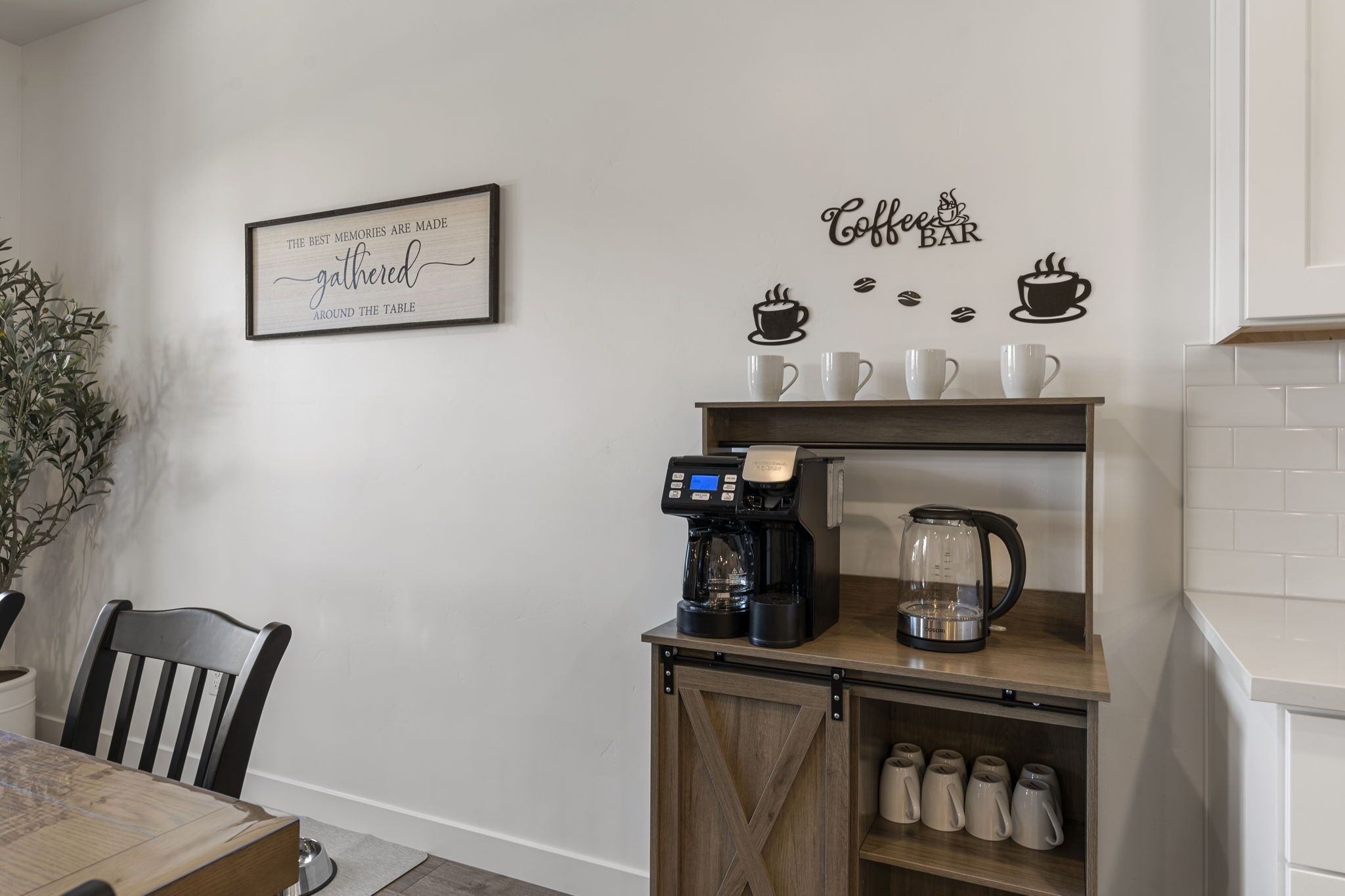 Eine Küchenzeile mit einer Kaffeestation, inklusive Kaffeemaschine, Tassen und Wasserkocher. An den Wänden befinden sich Dekorationen mit Kaffee-Bezug.