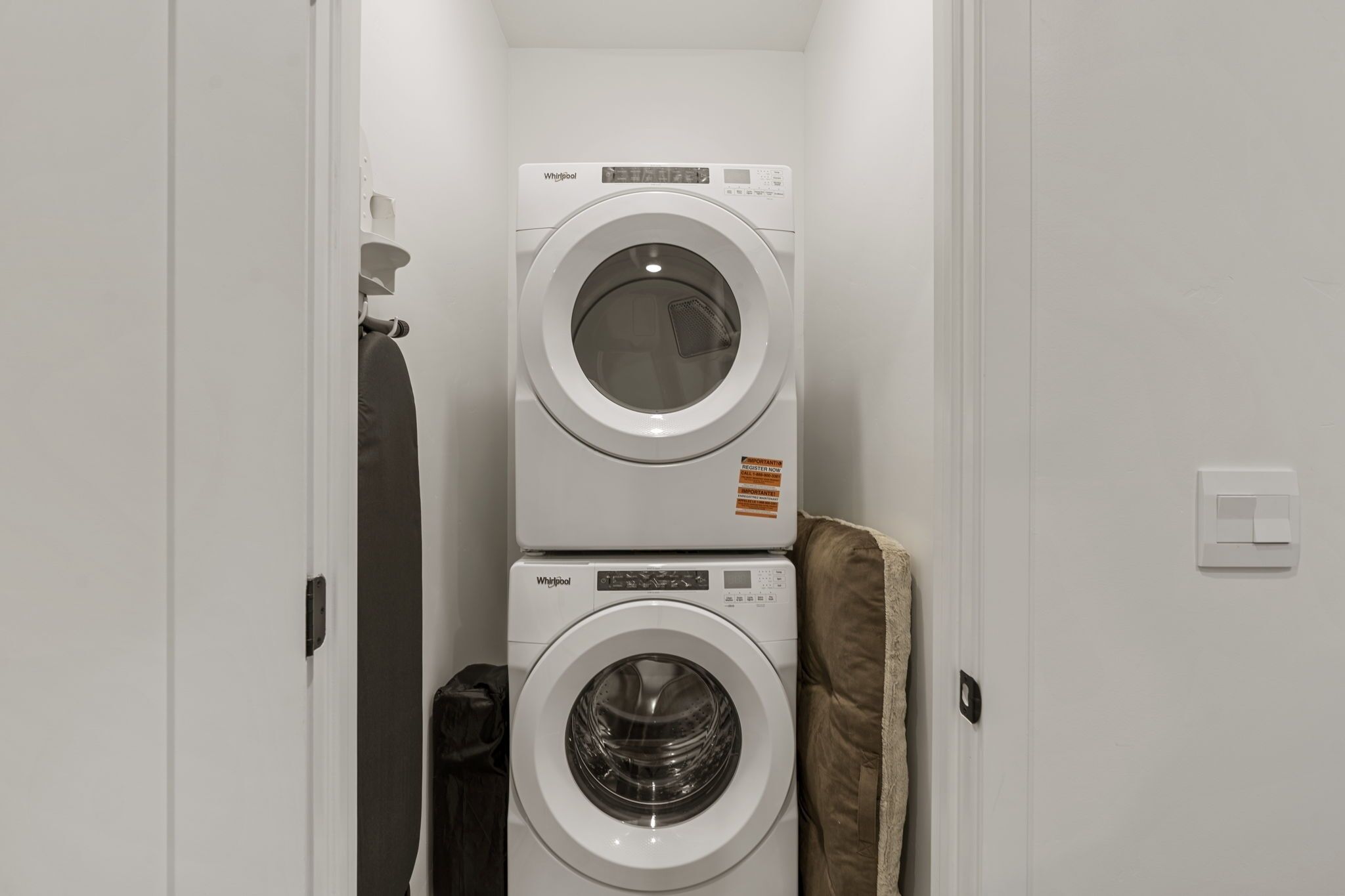 A laundry room with two stacked Whirlpool washing machines and a towel rack.