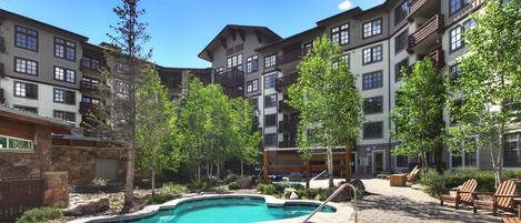A pool area with a hot tub, lounge chairs, and a stone wall.