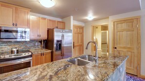 A kitchen with granite countertops, stainless steel appliances, wooden cabinets, and a built-in oven.