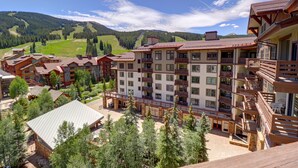 A multi-story hotel with balconies, a courtyard, and a mountainous backdrop.