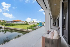 A modern building with a view of a calm water body and a well-maintained lawn. - Ostentatious Home | Short Walk to Beach, Food & Fun (Marco Island)
