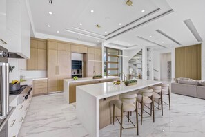 A modern kitchen with a central island, bar stools, and a built-in oven.