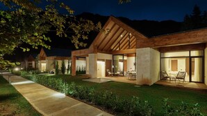A modern hotel with a spacious outdoor patio, large windows, and a well-lit entrance. - Terra Homes (Kolasin)