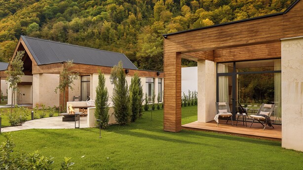 A modern house with a patio, a fireplace, and a view of a forested hill. - Terra Homes (Kolasin)