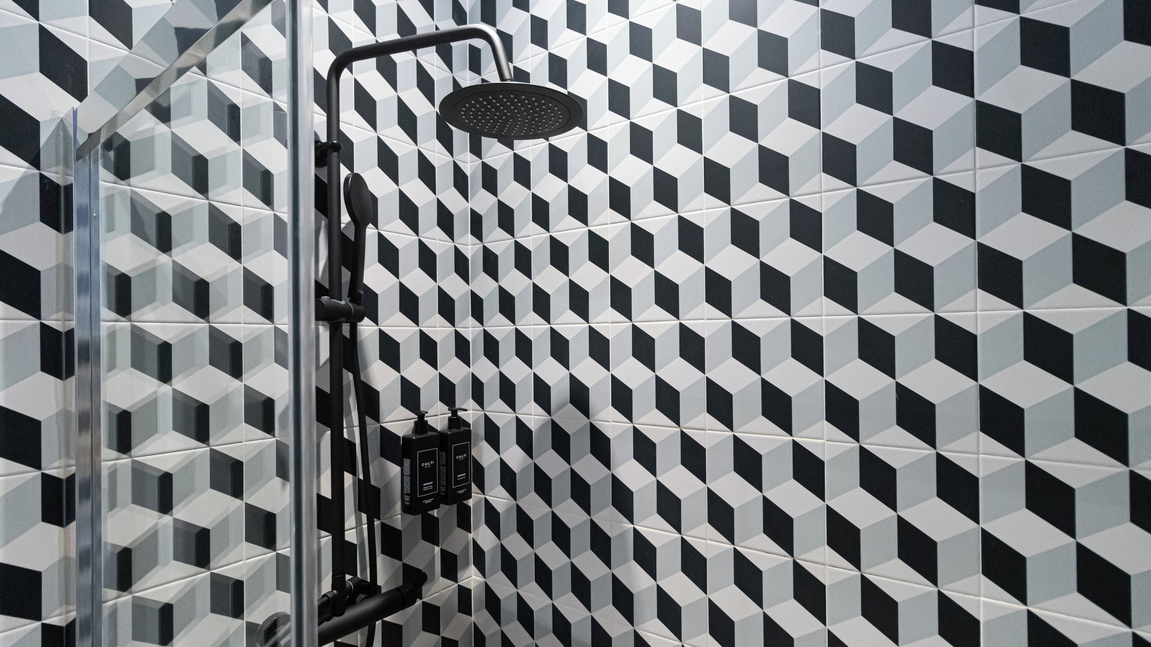 A shower with a geometric tile pattern on the wall.