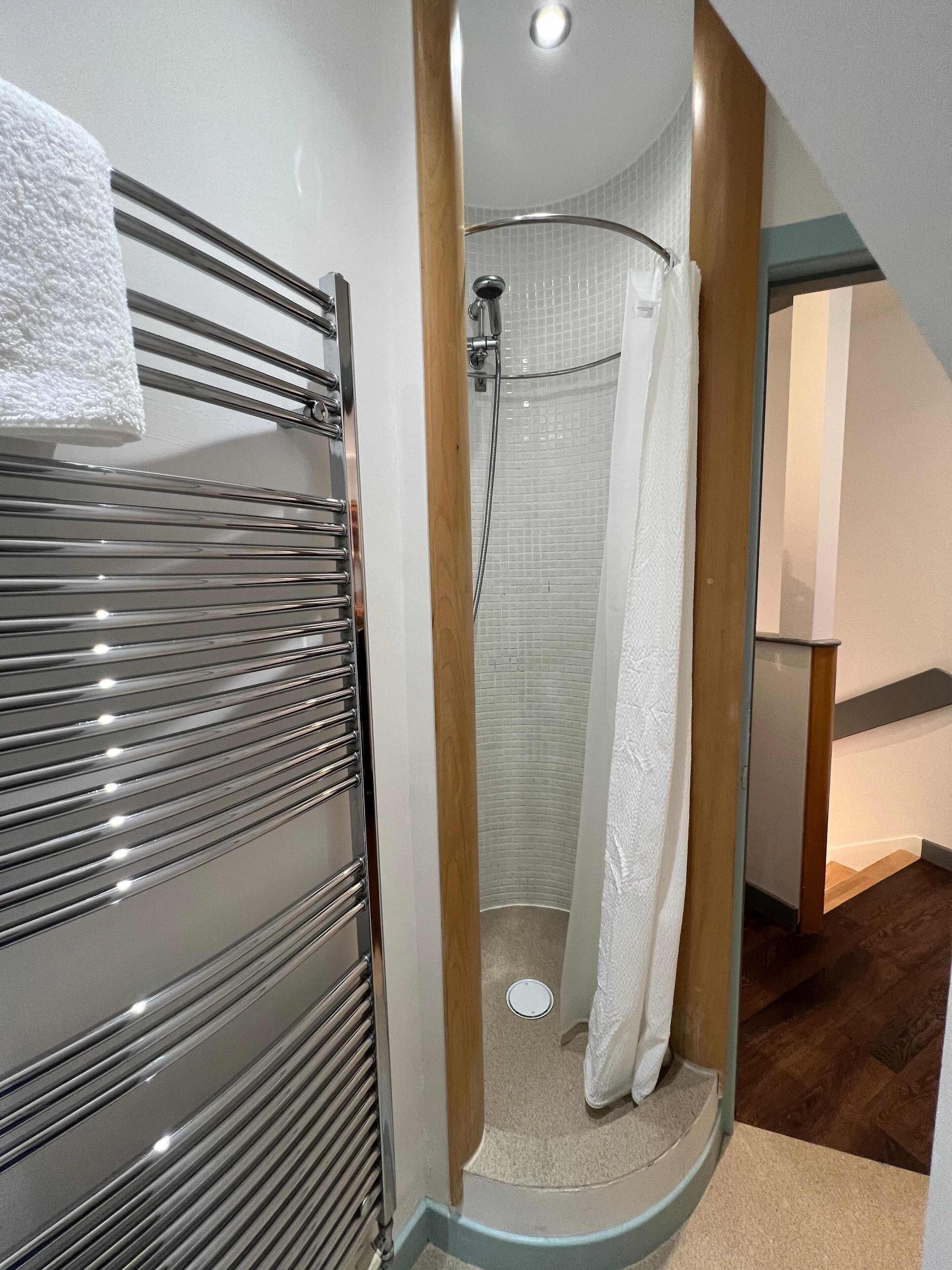 Une salle de bain moderne avec une douche à parois de verre, un porte-serviettes et un plancher en bois.