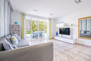 A modern living room with a sofa, TV, and a dining area with chairs and a table.