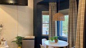 Une cuisine compacte équipée d’un grille-pain, d’un petit réfrigérateur et d’un coin repas avec une table ronde et des chaises blanches.
