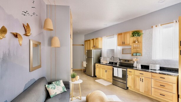 Une cuisine moderne avec des meubles en bois, des appareils électroménagers en acier inoxydable et un canapé gris.