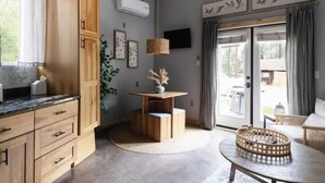 Une cuisine moderne avec des meubles en bois, une table ronde et un téléviseur fixé au mur.