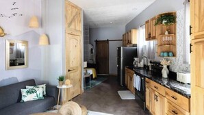 Une cuisine moderne avec des meubles en bois, un réfrigérateur noir et un plan de travail équipé de divers appareils électroménagers.