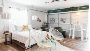 Um quarto moderno com uma cama, duas cadeiras de estrutura branca e um pequeno tapete branco.