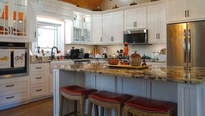 A modern kitchen with white cabinets, stainless steel appliances, and a marble countertop.