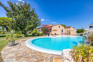 A swimming pool with stone tiles, a house with a tiled roof, and a large tree. - Country House 'L'évaroma' with Private Pool, Wi-Fi and Air Conditioning (Campagne)