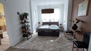 A modern bedroom with a large bed, a hanging light fixture, a wooden floor, and a view of the city. - Apartment 'Vogelnest' with Shared Pool, Shared Terrace and Wi-Fi (Mühlhausen/Thüringen)
