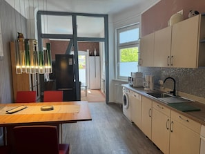 A modern kitchen with a dining area, a washing machine, and a large window. - Apartment 'Vogelnest' with Shared Pool, Shared Terrace and Wi-Fi (Mühlhausen/Thüringen)