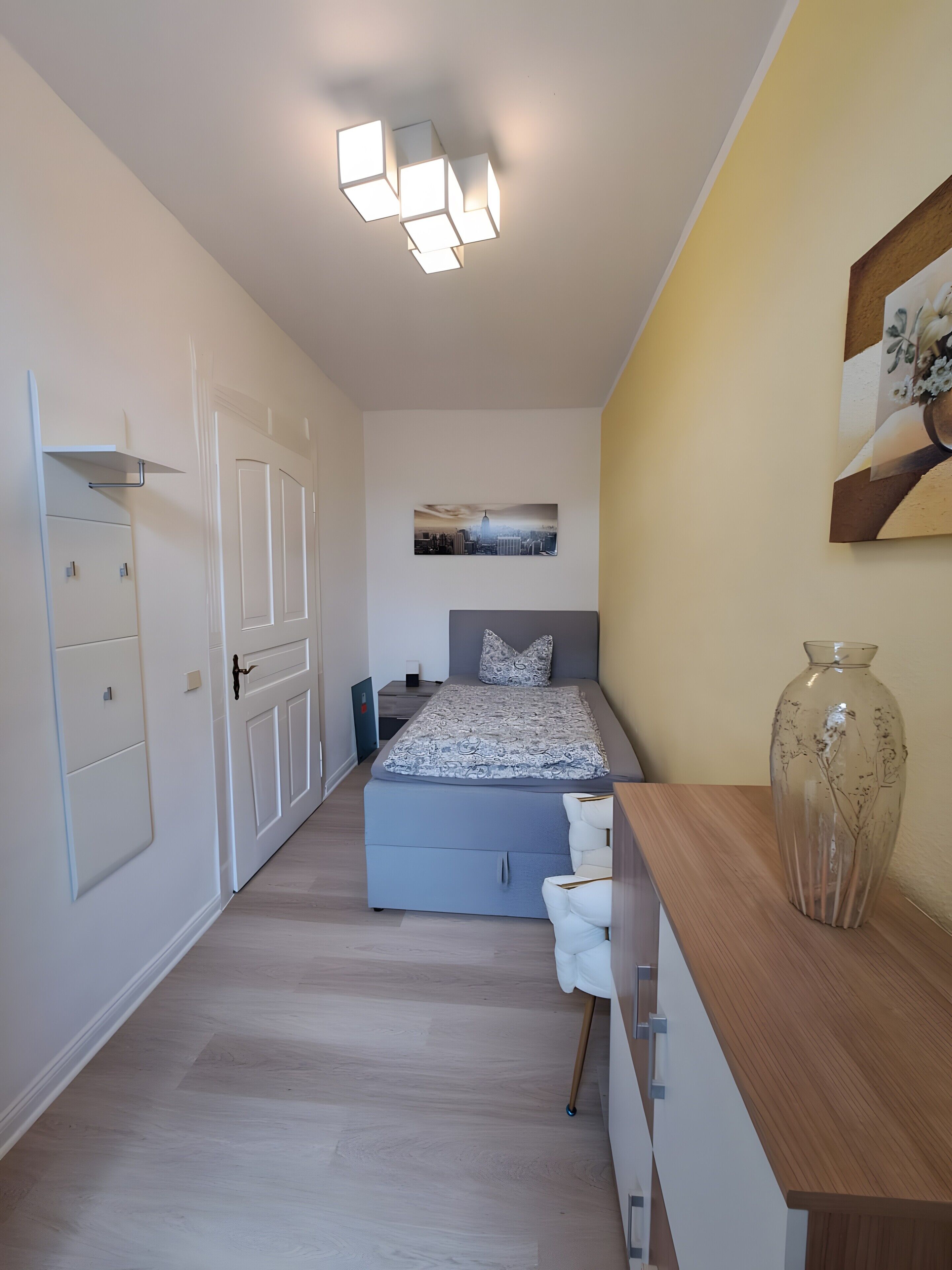 A bedroom with a bed, bedside table, and a vase.