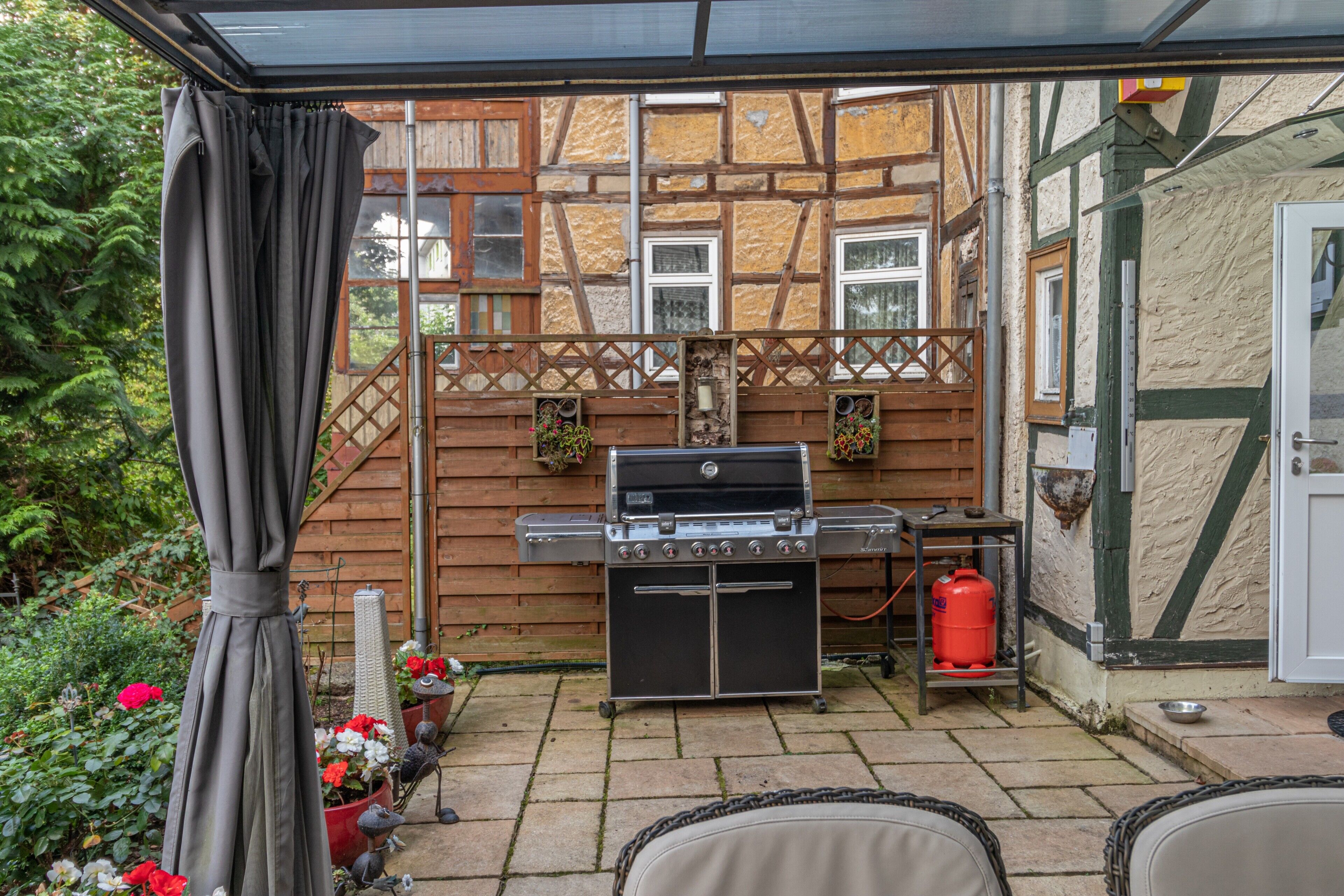 A patio with a grill, outdoor seating, and a wooden fence.