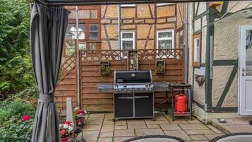 A patio with a grill, outdoor seating, and a wooden fence.