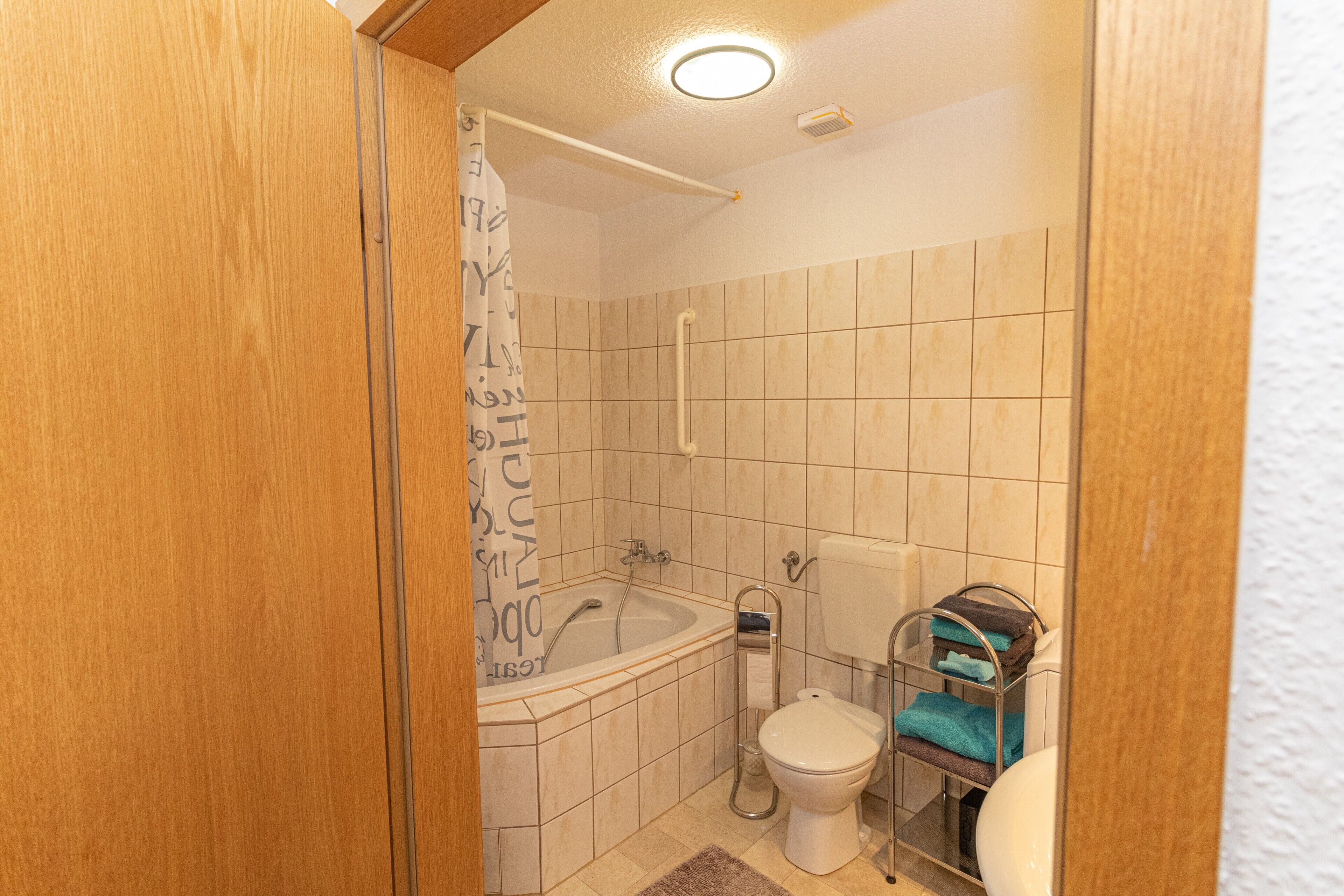 A bathroom with a bathtub, toilet, and shower curtain.