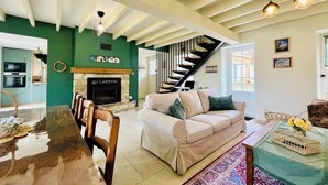 A spacious living room with a fireplace, a staircase, and a dining area. - Les Chatons - Gite au coeur de la campagne (Fresville)