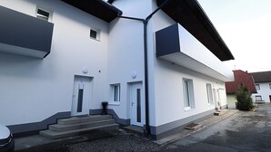 A two-story building with a white facade, a black roof, and a small balcony on the upper floor. - Pöckau 32 Smart Rooms Self Check In (Arnoldstein)