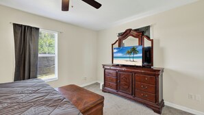 A bedroom with a bed, a dresser, a ceiling fan, and a window with curtains. - Spacious home with 7 beds, home gym, office with oversized backyard. (Fort Myers)