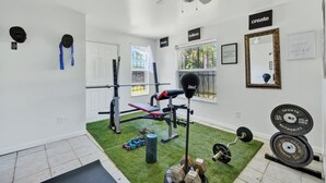 A home gym with a ceiling fan, weight bench, dumbbells, and a mirror. - Spacious home with 7 beds, home gym, office with oversized backyard. (Fort Myers)