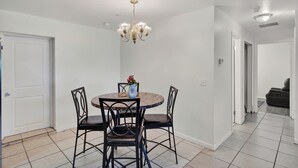 A dining area with a round table, four chairs, a chandelier, and a vase with flowers. - Spacious home with 7 beds, home gym, office with oversized backyard. (Fort Myers)