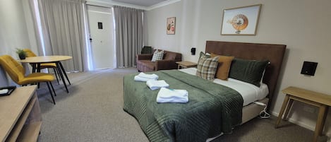 A hotel room with a bed, a desk, a chair, a couch, and a table.