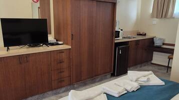 A hotel room with a bed, a TV, a desk, a wardrobe, and a bathroom.