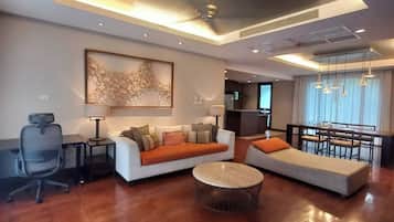 A modern living room with a sofa, armchairs, a coffee table, and a dining area with a table and chairs.