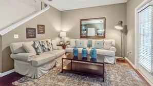 A living room with a sofa set, coffee table, decorative vases, a lamp, and wall art.