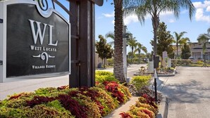 A sign for West Lucaya Village Resort with a landscaped entrance featuring various plants.
