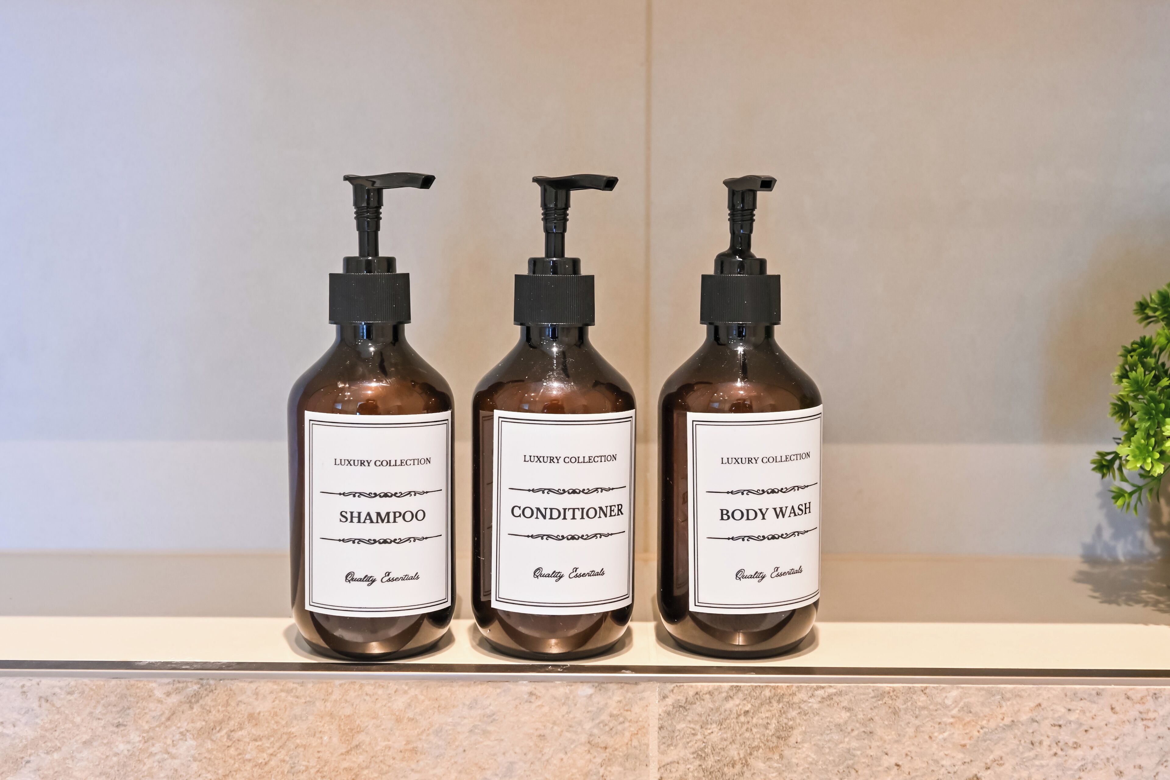 Trois bouteilles de shampoing, d’après-shampoing et de gel douche, posées sur une étagère.