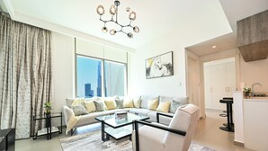 A modern living room with a sofa, coffee table, and a view of the cityscape through large windows. - Burj Khalifa View - 2 BR - PS5 - Pool (Dubai)
